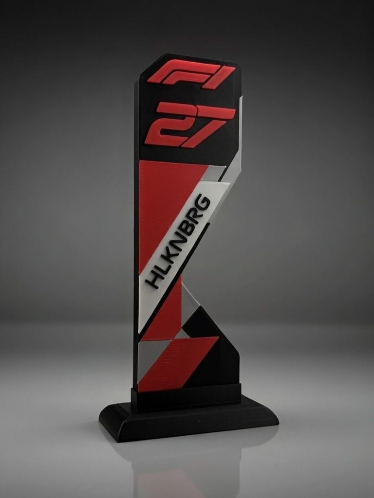 Ein stilisierter F1-Trophäe mit rot-schwarz-weißen Designelementen.