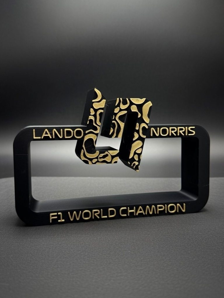 Schwarzer Aufsteller mit goldenen Verzierungen und der Inschrift "Lando Norris F1 World Champion".